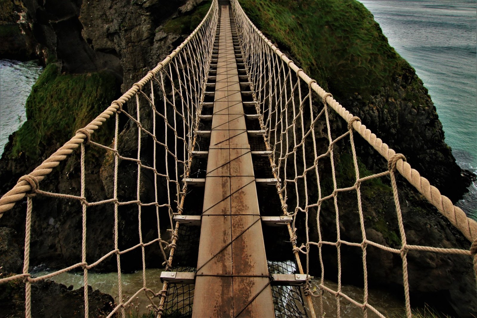 Eine schmale Hängebrücke verbindet zwei Felsküsten.