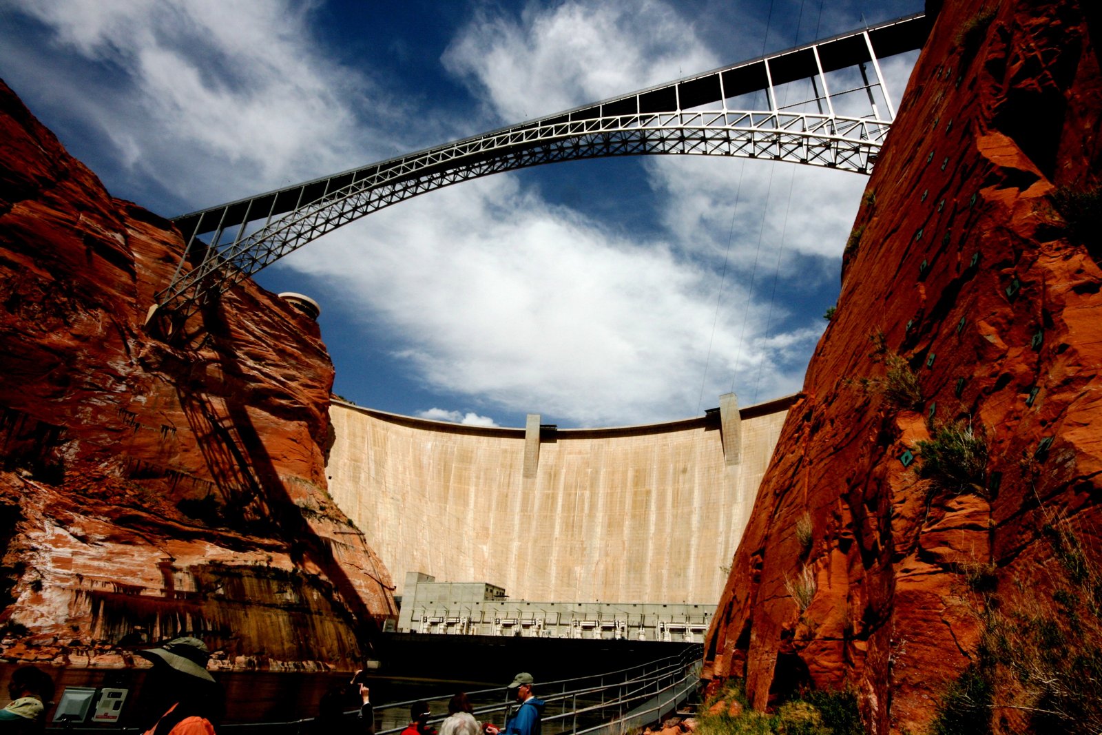 Eine Bogenbrücke überspannt eine Schlucht über einer Staumauer.