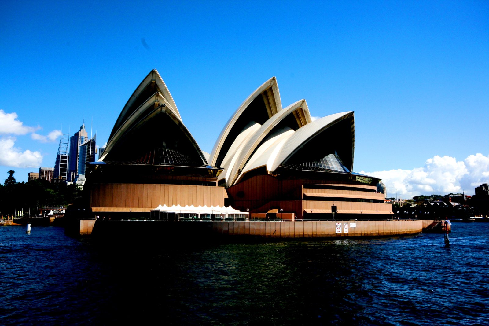Die Oper von Sydney am Wasser unter blauem Himmel.